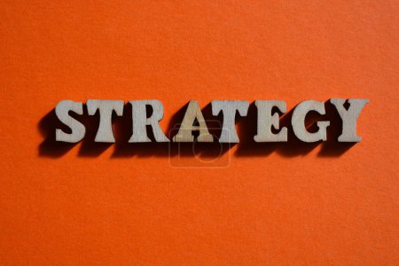 Téléchargez les photos : Stratégie, mot en alphabet bois lettres isolées sur fond orange - en image libre de droit
