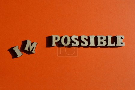 Foto de Impossible, Possible, words in wooden alphabet letters isolated on bright orange background - Imagen libre de derechos
