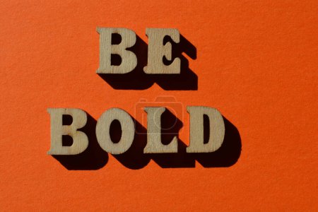 Téléchargez les photos : Soyez audacieux, mots en lettres de l'alphabet en bois isolés sur fond orange vif - en image libre de droit