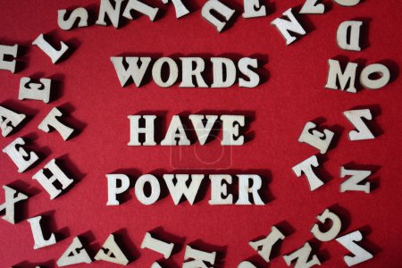 Téléchargez les photos : Mots ont le pouvoir, phrase entourée de lettres de l'alphabet en bois aléatoire isolé sur fond rouge - en image libre de droit