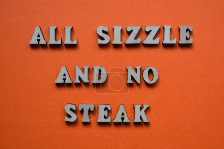 Foto de All Sizzle and No Steak, frase en letras de alfabeto de madera aisladas sobre fondo naranja - Imagen libre de derechos