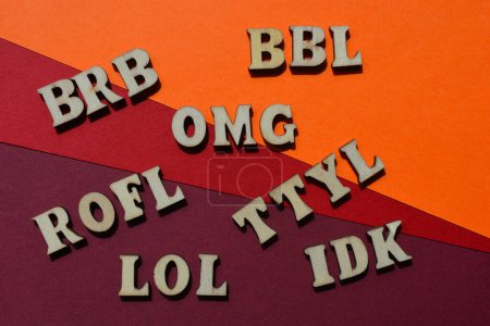 Photo for Acronyms used in texting, including BRB, Be Right Back, ROFL, Rolling on Floor Laughing, TTYL, Talk to you Later, in wooden alphabet letters isolated on background - Royalty Free Image