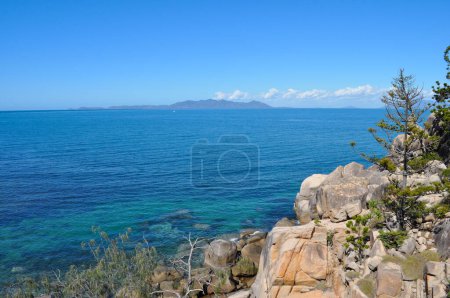 Photo for Granite rocks and Hoop pines on the coast, seen from The Gabul Way, a raised floating walkway linking Nelly Bay and Geoffrey Bay on Magnetic Island, looking towards the mainland, Queensland, Australia - Royalty Free Image