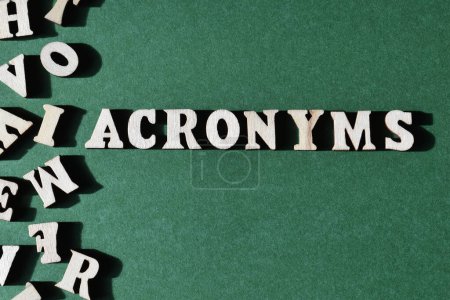 Acronymes, mots et lettres aléatoires de l'alphabet en bois isolés sur fond vert avec espace de copie