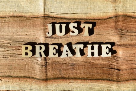 Just Breathe, words in wooden alphabet letters isolated on natural wood grain texture background as banner headline
