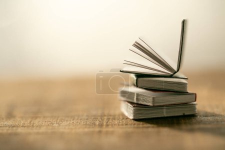 Téléchargez les photos : Pile de livres sur une table en bois sur un fond flou clair. soft focus.Learning et symbole de la connaissance.Lecture et éducation.Littérature et lecture - en image libre de droit