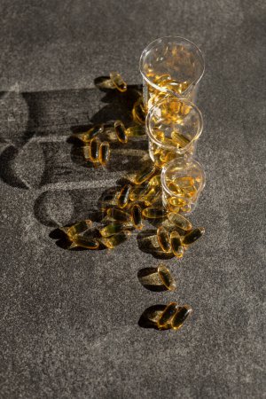 Foto de Aceite de pescado en frascos de laboratorio transparentes sobre un fondo de pizarra negra en luz dura brillante con sombras. Omega-3.ácidos grasos omega. Suplementos naturales y vitaminas. - Imagen libre de derechos