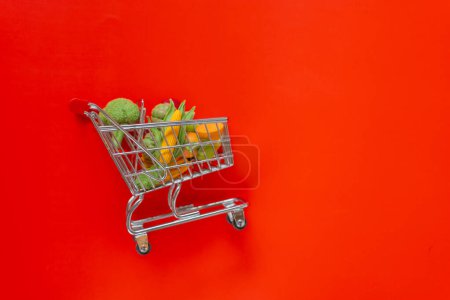 Photo for Food prices.Vegetables and fruits price increase.food crisis.supermarket trolley with groceries and up arrow on a red background.Food grocery consumer basket concept. - Royalty Free Image