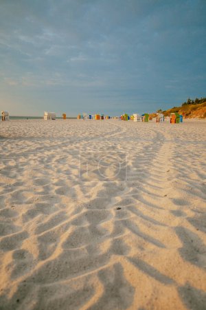 Strandhütten auf weißem Sand. Strandkörbe an der Nordseeküste. Urlaub an der Nordsee. Strände der friesischen Inseln in Deutschland. Sommerstimmung. 