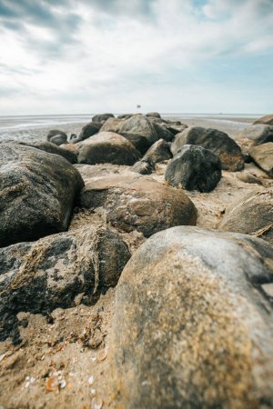  rochers sur la plage à marée base.Wadden Sea Coast.Stone groyne gros plan sur fond de ciel nuageux.. Fond d'écran photo marine.Nature de la côte de la mer du Nord. Îles Frisonnes d'Allemagne. 