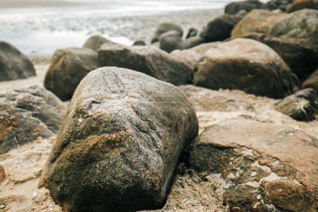 Stone Groyne auf Strand background.Stone Felsbrocken am Strand bei Ebbe. Marine Fototapete. Natur der Nordseeküste. Friesische Inseln in Deutschland. Ruhe auf dem Meer. 