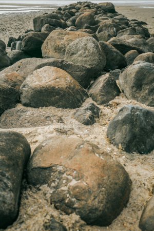 Groyne en pierre gros plan sur fond de plage.Rochers de pierre sur la plage à marée bas.Papier peint photo marine.Nature de la côte de la mer du Nord. Îles Frisonnes d'Allemagne.