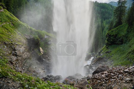 Wasserfall fällt sanft die alpinen Berge hinunter. Wasser fließt reibungslos. Stürmischer Wasserstrom mit Tropfen und Spritzern. Abwärtsbewegung des Wassers