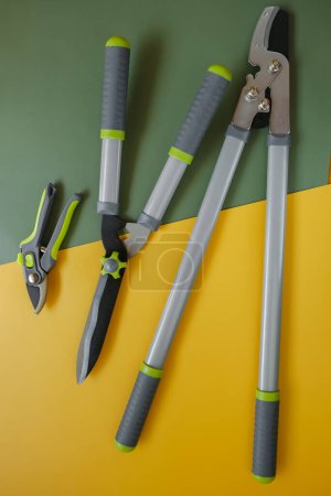 Tijeras de podar, cortarramas y cortadoras de setos en un fondo amarillo verde.Equipo de jardín. Herramientas para podar y recortar