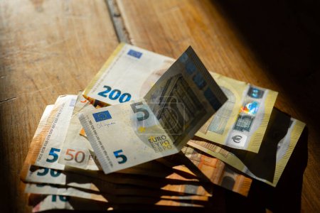 Billetes de euros en una mesa de madera.Billetes de euros en una mesa de madera en una tira de luz.Ingresos en países europeos. 