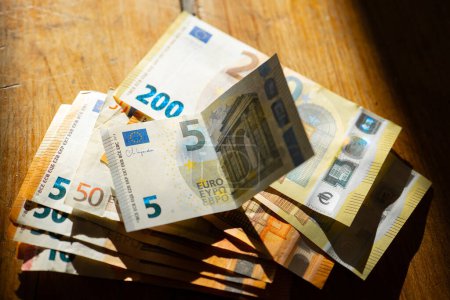 Euro Dinero en una mesa de madera en una franja de luz.Ingresos en los países europeos. Paquete de billetes en euros Pagos en efectivo en los países de la UE.Ganancias y gastos en la zona euro. 