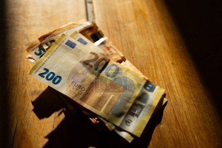 billetes de euro en una mesa de madera en una franja de luz.Ingresos en los países europeos. Paquete de billetes en euros Pagos en efectivo en los países de la UE.Ganancias y gastos en la zona euro. 