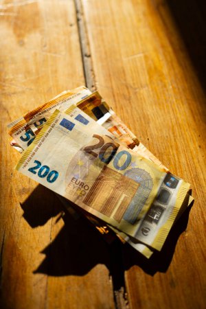 billetes de euro en una mesa de madera en una franja de luz.Ingresos en los países europeos. Billetes en euros.Pagos en efectivo en los países de la UE.Ganancias y gastos en la Eurozona. 