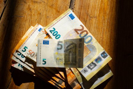 Euro Money.euro billetes en una mesa de madera en una tira de luz.Ingresos en los países europeos. Paquete de billetes en euros Pagos en efectivo en los países de la UE.Ganancias y gastos en la zona euro. 