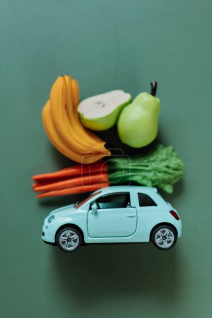 groceries online and delivered to their doorstep. Delivery of vegetables and fruits. blue car with a shopping basket on the roof with fruits and vegetables on a green background. grocery shopping and
