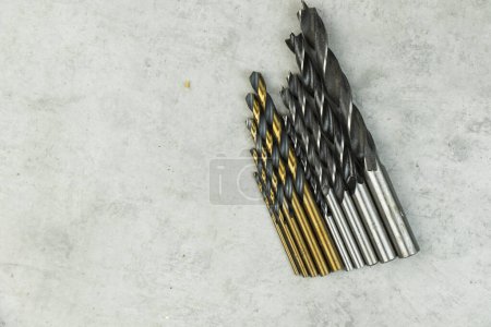 Foto de Cabezales de taladro inalámbricos de acero inoxidable en el fondo gris, cabezas de taladro de madera, pared y metal - Imagen libre de derechos
