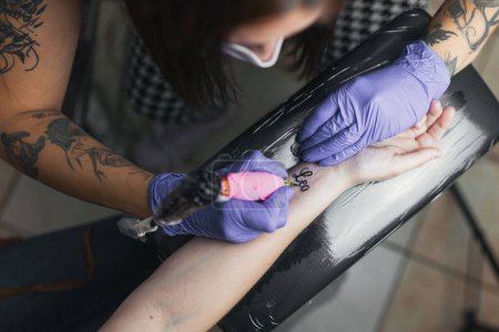 Photograph of tattoo artist tattooing close up.