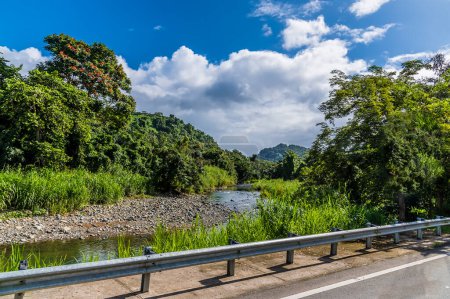Téléchargez les photos : A view towards a river in the foothills of the tropical rainforest in Puerto Rico on a bright sunny day - en image libre de droit