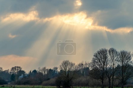 Ein Blick auf die Sonne, die im Frühling durch die Wolken über dem Riverside Park in Stamford, Lincolnshire, Großbritannien bricht