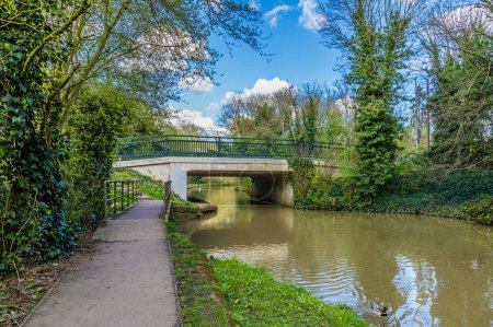 A view along the canal path towards a road bridge over the Grand Union Canal in Aylestone Meadows, Leicester, UK in Springtime