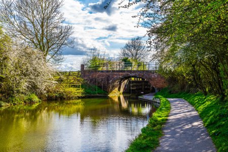 A view towards a footbridge and lock gates on the Grand Union Canal in Aylestone Meadows, Leicester, UK in Springtime