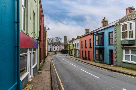 Téléchargez les photos : Une vue au-delà des maisons colorées vers les ruines du château sur la route principale dans Narberth, Pemborkeshire, Pays de Galles au printemps - en image libre de droit
