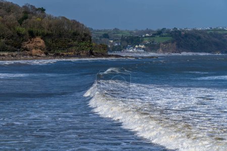 A view of surf breaking off the beach in the village of Saundersfoot, Wales on a bright spring day