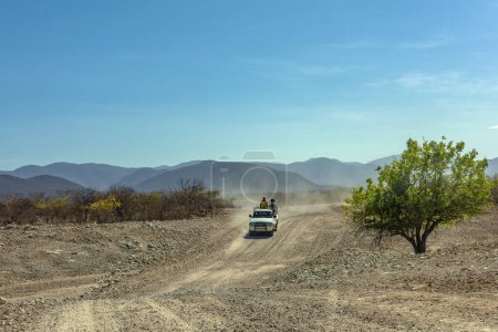 Photo for KUNENE RIVER, NAMIBIA-DECEMBER 12, 2020: Car on a dusty gravel road along the Kunene River in northern Namibia - Royalty Free Image