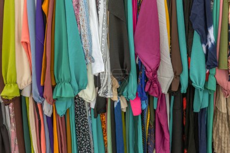Téléchargez les photos : Vêtements colorés usagés suspendus sur un rack à un marché aux puces - en image libre de droit
