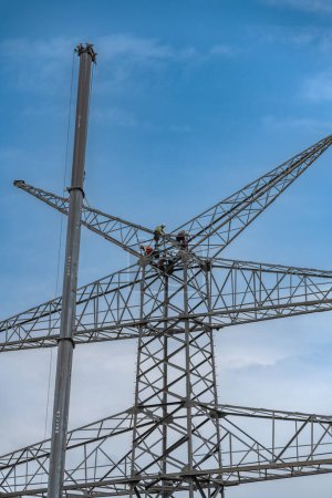 Téléchargez les photos : FRANKFURT AM MAIN, ALLEMAGNE-19 JUIN 2023 : ouvriers assemblant un poteau électrique à haute altitude - en image libre de droit