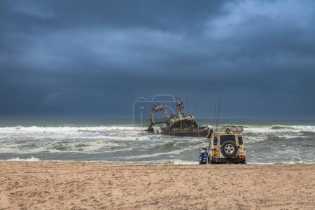 Photo for SWAKOPMUND, NAMIBIA-DECEMBER 26, 2023:  Deep sea fishermen at the wreck of the fishing vessel Zeila, Skeleton Coast, Namibia - Royalty Free Image