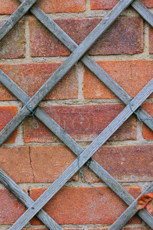 A brick wall with wooden trellis
