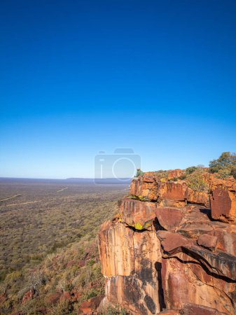 Téléchargez les photos : Un local assis sur un rocher, profitant de la vue spectaculaire sur le plateau, Plateau Waterberg, Namibie. - en image libre de droit
