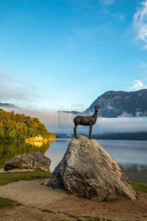 Photo for Early morning view at Lake Bohinj in Bohinj with the statue of Goldhorn (Zlatorog) on the rock, Bohinj, Slovenia. - Royalty Free Image
