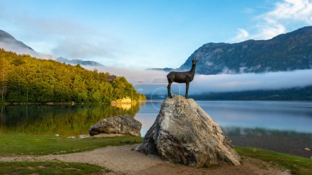 Photo for Early morning view at Lake Bohinj in Bohinj with the statue of Goldhorn (Zlatorog) on the rock, Bohinj, Slovenia. - Royalty Free Image