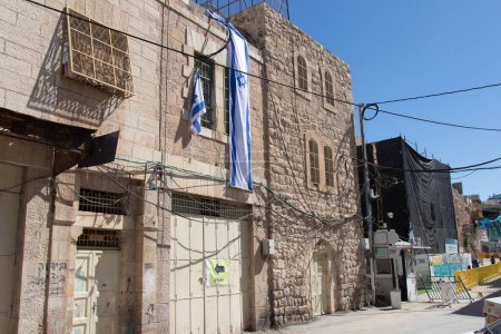 Foto de Casa judía en el distrito musulmán de la ciudad de Hebrón. Bandera de Israel colgando de la casa de la ciudad de Hebrón. - Imagen libre de derechos