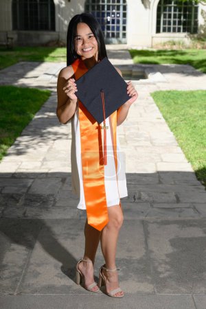 Téléchargez les photos : Jeune fille américaine asiatique attrayante avec chapeau et robe se préparant pour l'obtention du diplôme d'université - en image libre de droit