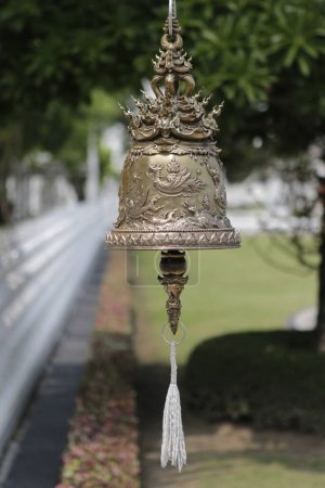 Photo for Vertical Selective focus photo of a Sunlit Decorative bell charm hanging in a park theme setting blur background, no people. - Royalty Free Image