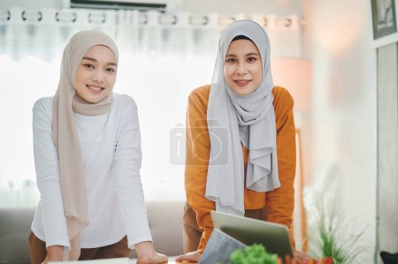 Téléchargez les photos : Deux femmes musulmanes portant le foulard hijab debout dans le bureau. - en image libre de droit