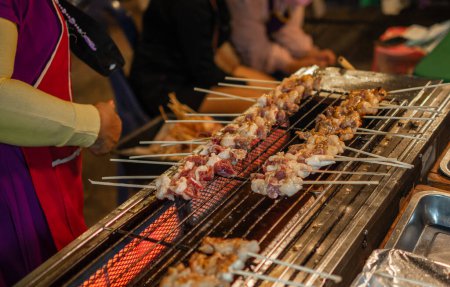 Photo for The pork is skewered on a stick and grilled on a charcoal stove. To wait for the pork to be cooked to be sold on the sidewalk. - Royalty Free Image
