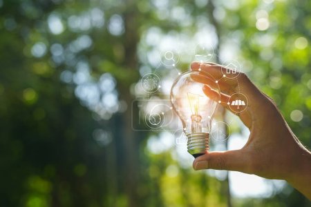 Photo for Hand holding light bulb against nature, icons energy sources for renewable, - Royalty Free Image