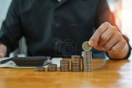 Photo for Coins a men's hand  placed and sorted coins on a wooden board. - Royalty Free Image