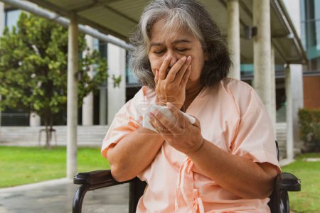 Foto de Anciana asiática sentada en silla de ruedas y paciente de hospital que sufre de neumonía y tos en riesgo de cáncer de pulmón se sorprende al ver esputo ensangrentado: Mujer anciana se sorprendió ver el esputo ensangrentado. - Imagen libre de derechos