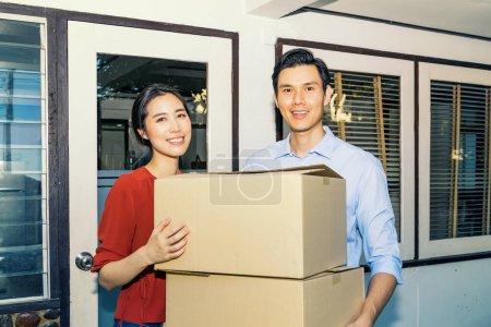 Téléchargez les photos : Bonheur souriant famille asiatique couple tenant des boîtes en carton pile pour se déplacer vers une nouvelle maison avec des visages souriants : Déménagement de la maison pour transporter les choses nécessaires à un nouveau concept de lieu - en image libre de droit