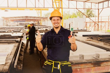 Téléchargez les photos : Homme plâtrier ouvrier artisan dans l'usine chantier de construction mur en béton préfabriqué pouces vers le haut de travailler avec bonheur et compétence pendant la marche de l'homme d'affaires inspecter le site de mur en béton préfabriqué. - en image libre de droit